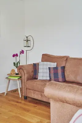 a living room with a brown couch and a table at Shepherds Rest in Llandyssil