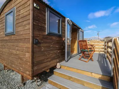 a wooden tiny house with a chair on a deck at Claerwen in Llandrindod Wells