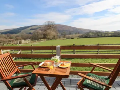 a table and chairs on a deck with a view of a field at Claerwen in Llandrindod Wells