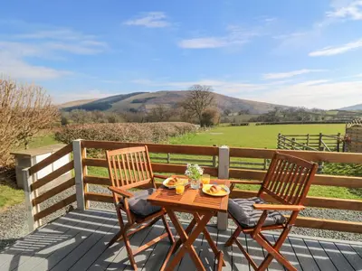a table and chairs on a deck with a view of a field at Elan in Llandrindod Wells