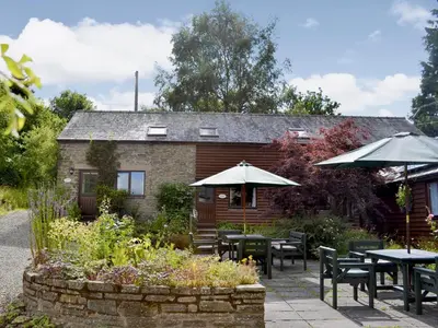 a patio with tables and umbrellas in front of a building at Stable Cottage in Leintwardine
