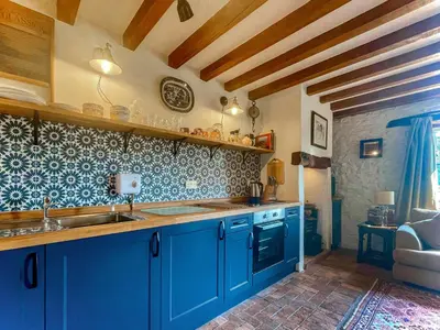 a kitchen with blue cabinets and a sink at Stable Cottage in Leintwardine