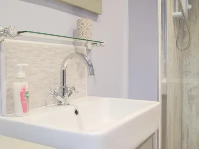a white sink in a bathroom with a shelf above it at Llain Cottage in Llanina