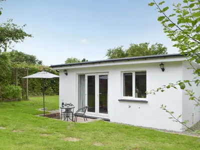 a white cottage with a table in a yard at Llain Cottage in Llanina