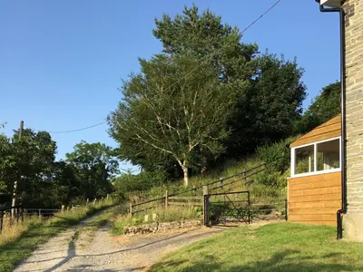 a barn with a fence and a tree on a hill at Lower Farm in Llanfihangel Rhydithon
