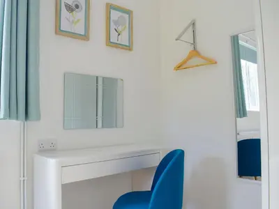 a white desk with a blue chair next to a mirror at The Lodge At Forbury Cottage in Kimbolton