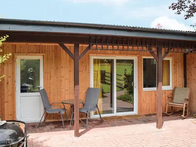 a house with a patio with chairs and a table at The Lodge At Forbury Cottage in Kimbolton