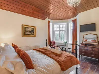 a bedroom with a large bed with a wooden ceiling at Groudd Hall in Cerrigydrudion
