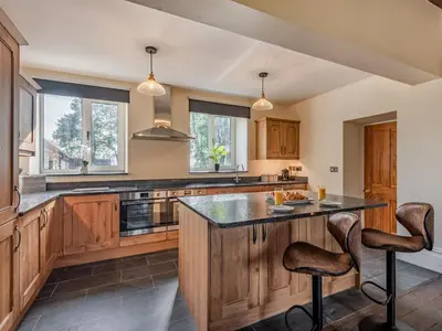 a kitchen with wooden cabinets and a large island at Groudd Hall in Cerrigydrudion