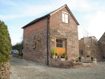 a brick house with a wooden door and potted plants at The Granary in Clee Saint Margaret