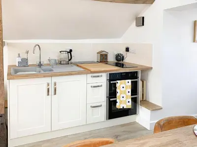 a kitchen with white cabinets and a black oven at The Granary in Clee Saint Margaret