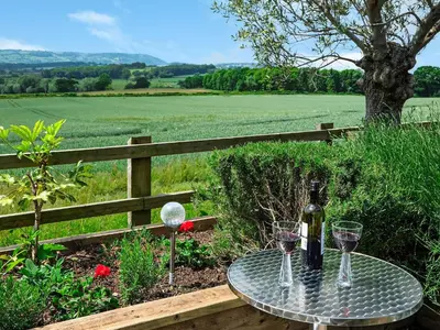 a table with two glasses and a bottle of wine at Hop Kiln Barn in Staunton on Wye