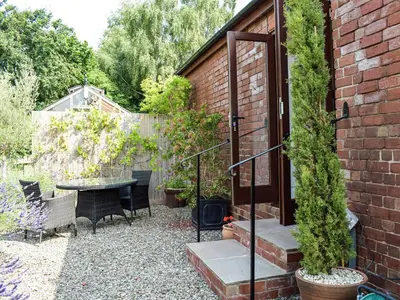 a patio with a table and chairs in a garden at Hop Kiln Barn in Staunton on Wye