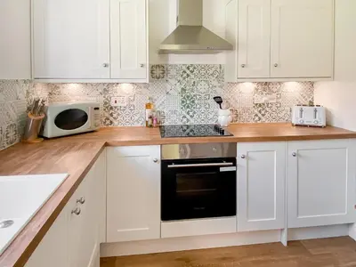a kitchen with white cabinets and a microwave at Rose Cottage in Blakemere