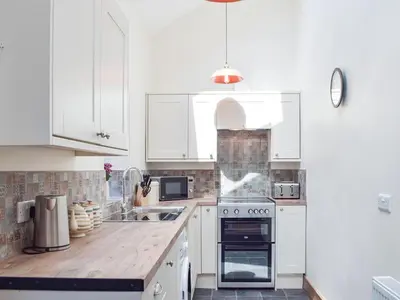 a kitchen with white cabinets and a wooden counter top at Uk34913 - Bwlchgraig Fach in Nantcwnlle