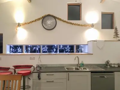 a kitchen with a sink and a clock on the wall at Llety'r Saer in Pen-y-bont-fawr