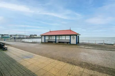 a building with a red roof next to the ocean at 2 Bed in Aberystwyth oc-bow200 in Aberystwyth
