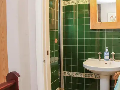 a green tiled bathroom with a sink and a shower at 55 Corve Street in Ludlow
