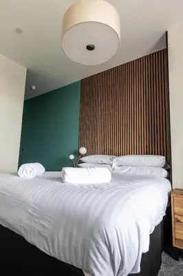 a bedroom with a large white bed with a green wall at Ty Belgrave in Aberystwyth