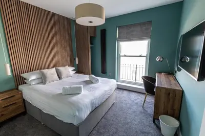 a bedroom with a large bed and a window at Ty Belgrave - Apartment 3 in Aberystwyth