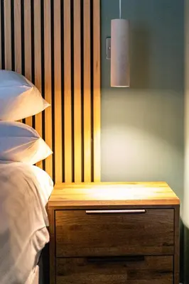 a bed with a wooden night stand next to a bed at Ty Belgrave - Apartment 3 in Aberystwyth