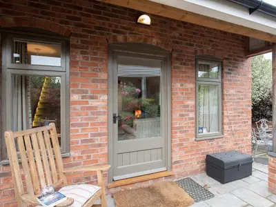 a brick house with a gray door and a chair at Top House in Forden