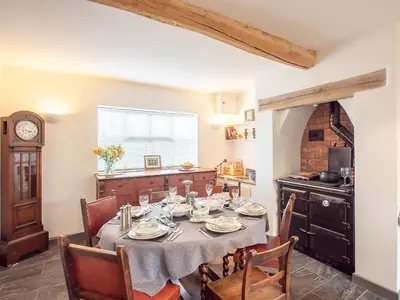 a dining room with a table and chairs and a clock at Top House in Forden