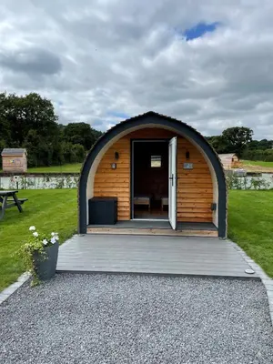 a small wooden building with a door in a yard at Eastridge Glamping - Camping Pods in Shrewsbury