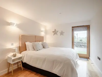 a white bedroom with a large bed and a window at Hafan Yr Haul in Arthog
