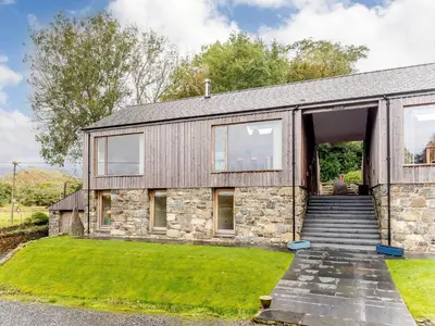 a stone house with a door and a grass yard at Hafan Yr Haul in Arthog