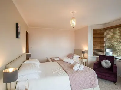 a bedroom with two beds and a chair at Brig-Y-Don in Aberaeron