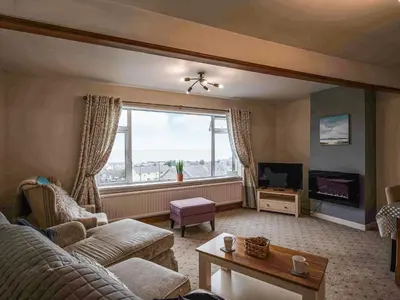 a living room with a couch and a large window at Brig-Y-Don in Aberaeron