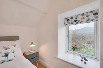 a bedroom with a window with a vase of flowers on a window sill at 1 Bed in Dolgellau oc-bow292 in Dolgellau