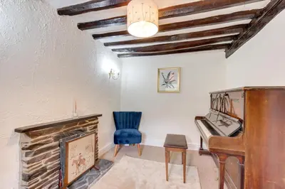 a living room with a piano and a blue chair at 3 Bed in Tywyn oc-bow248 in Abergynolwyn