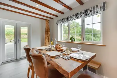 a dining room with a wooden table and some windows at 3 Bed in Aberystwyth oc-bow297 in Pentre-briwnant