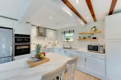 a kitchen with white cabinets and a table with a bowl of fruit at 3 Bed in Aberystwyth oc-bow297 in Pentre-briwnant