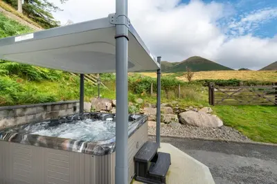 a hot tub with an umbrella in a garden at 3 Bed in Aberystwyth oc-bow297 in Pentre-briwnant