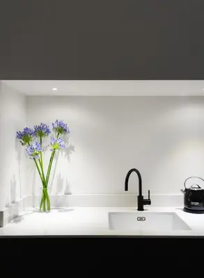 a kitchen counter with a sink and purple flowers in a vase at Deluxe Apartment in Historic Quarter near Beaches in Aberystwyth