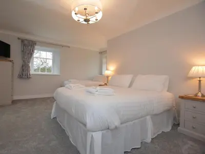 a bedroom with a white bed with two lamps and a window at Pengarreg Fawr in Aberystwyth
