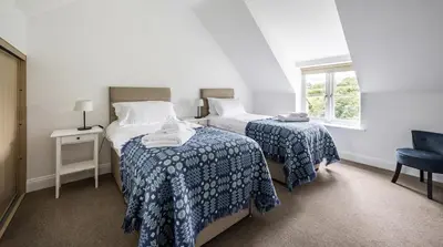 a bedroom with two beds and a window at Stunning Barn Conversion with HOT TUB and ALPACAS - Ty Cerrig Barn in Corwen