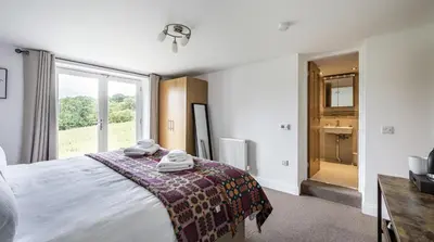 a bedroom with a bed and a large window at Stunning Barn Conversion with HOT TUB and ALPACAS - Ty Cerrig Barn in Corwen