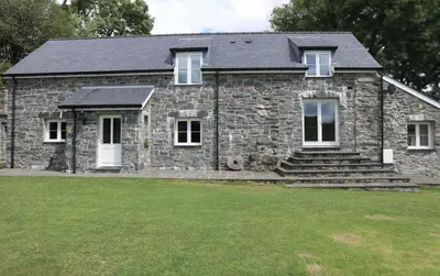 a stone house with a lawn in front of it at Romantic Couples' Getaway - at Ty Cerrig Barn with luxury hot tub in Corwen