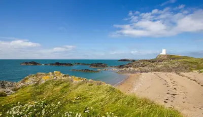 a lighthouse on the shore of a beach with the ocean at Romantic Couples' Getaway - at Ty Cerrig Barn with luxury hot tub in Corwen