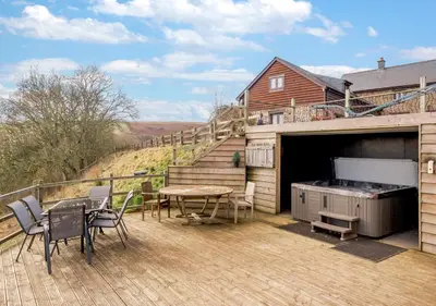 a patio with a barbecue and a table and chairs at Beacons View Farm Cottages in Merthyr Cynog