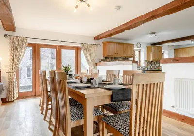 a kitchen and dining room with a wooden table and chairs at Beacons View Farm Cottages in Merthyr Cynog