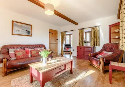 a living room with leather couches and a coffee table at Beacons View Farm Cottages in Merthyr Cynog