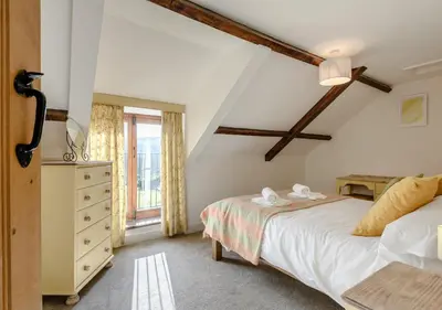 a bedroom with a bed and a dresser and a window at Beacons View Farm Cottages in Merthyr Cynog