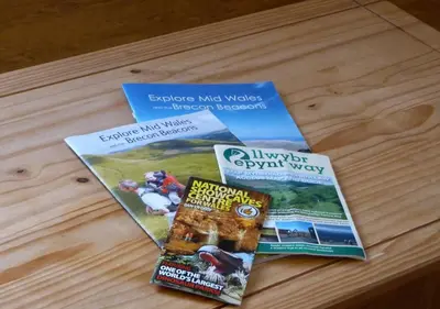 three magazines sitting on a wooden table at Beacons View Farm Cottages in Merthyr Cynog