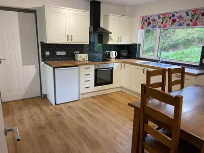 a kitchen with white cabinets and a wooden floor at 4 bedroom bungalow in peaceful countryside with log burner - Talar Deg, Capel Madog in Capel Madog
