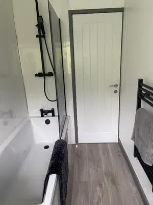 a bathroom with a white tub and a shower at 4 bedroom bungalow in peaceful countryside with log burner - Talar Deg, Capel Madog in Capel Madog
